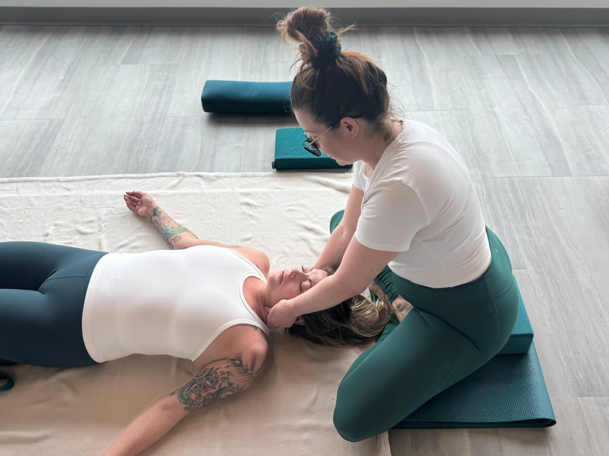 Stacey offering hands-on bodywork to a client resting on a floor mat